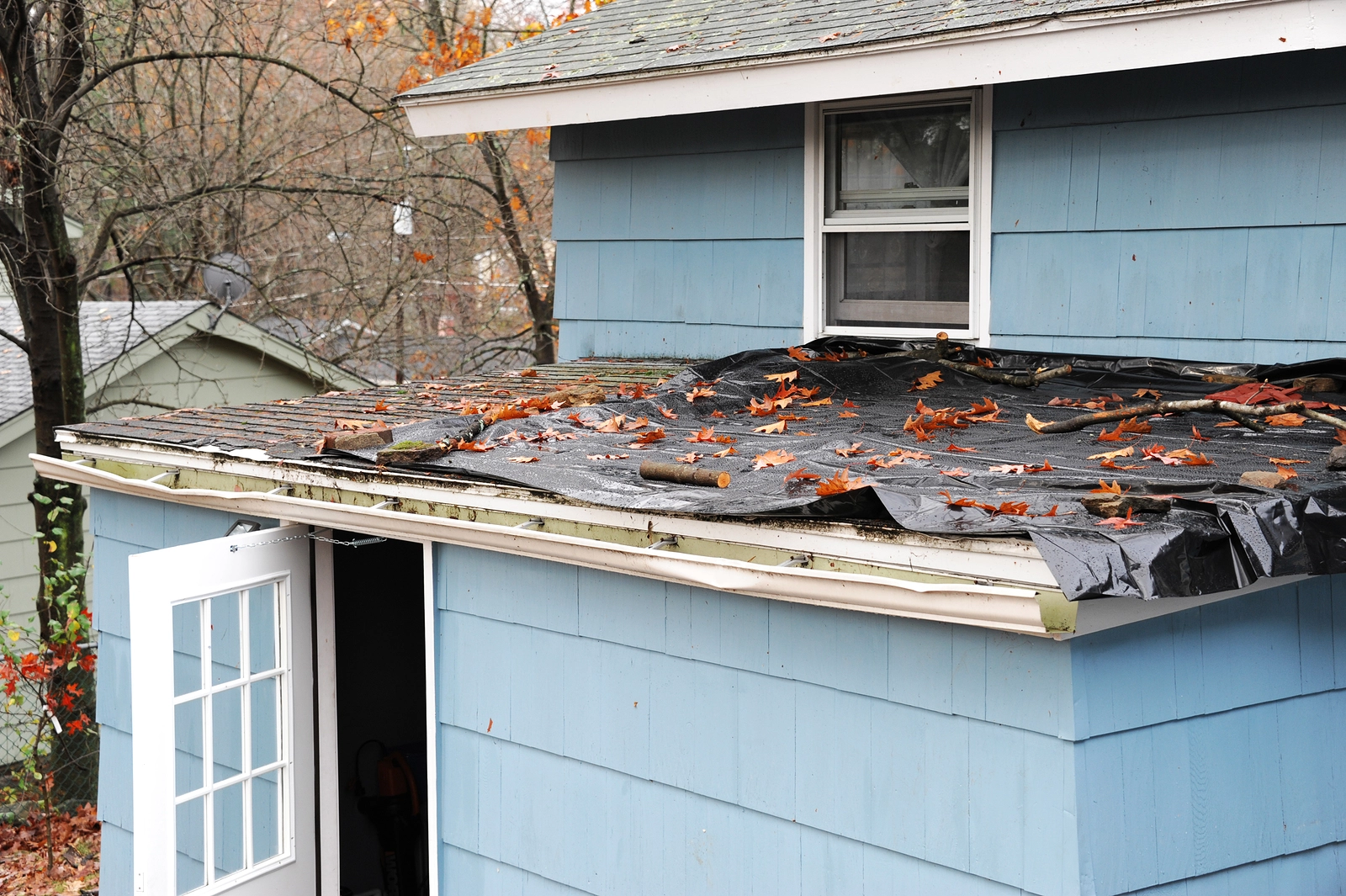 Residential roof damaged after a storm covered in plastic.
